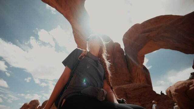 Female hiker looking around underneath beautiful natural canyon arches
