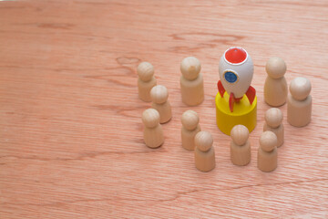 The wooden figures, clustered around a symbolic rocket, epitomized the success strategy of a cohesive team, reflecting the collective effort of teammates propelling the company towards global business