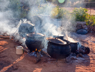 group of cast iron pot in the outdoors kitchen, cooking for a large event , african village .