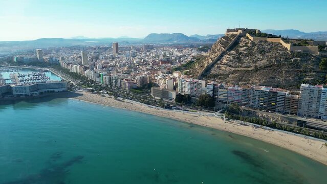 Video y tomas Aérea de Alicante desde la Playa del Postiguet sobre el mar  con el Castillo de Santa Barbara