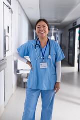 Portrait of happy asian female doctor standing in hospital corridor