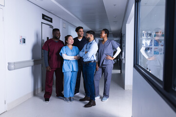 Fototapeta premium Happy diverse male and female doctors talking in hospital corridor