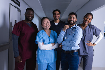 Portrait of happy diverse male and female doctors standing in hospital corridor