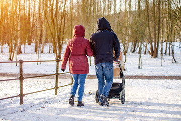 A married couple rolls a child in a wheelchair in the winter Park
