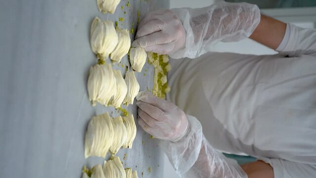 The Turkish pastry chef prepares oyster baklava  (Midye Baklava) and fills it with cream and pistachios , slow motion video, vertical video