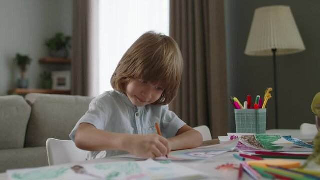 Boy diligently sketching vibrant rainbow with colored pencils at table and shows result. Heartwarming scene, beauty of children's creativity, ability to create happiness and radiate contagious smiles
