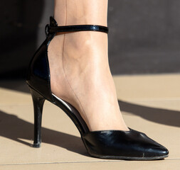 Legs of a girl in black stilettos on the paving slabs. Close-up