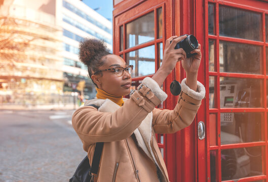 Amazing woman using camera against red  phonebox traveling around English city Enjoying travel concept Toned image