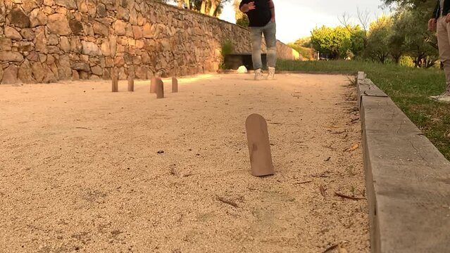 Male Throw Wooden Pin  and Miss During Scandinavian Molkky Game on Sandy Court at Sunset - Slow Motion