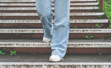 a womanl in jeans and sneakers walking down the stairs in the public park