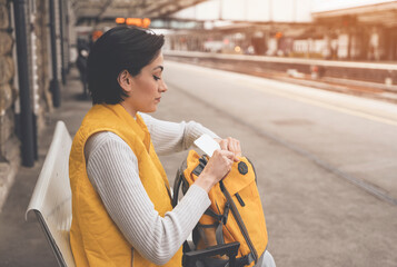 young woman holding passport and tickets, and waiting for train at railway station Enjoying travel...