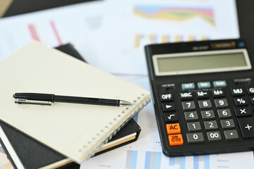 Calculator machine, notepad and financial documents on office table