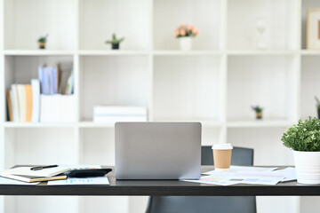 Comfortable workplace with laptop, documents and office supplies on black wooden table