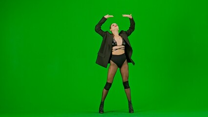 Framed on a green background, chromakey. Young woman wearing open clothing and jacket. Demonstrates a dance movement in the direction of high heels. She is sexy, plastic, rhythmic. Medium shot