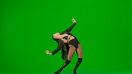 Framed on a green background, chromakey. Young woman wearing open clothing and jacket. Demonstrates a dance movement in the direction of high heels. She is sexy, plastic, rhythmic. Medium shot