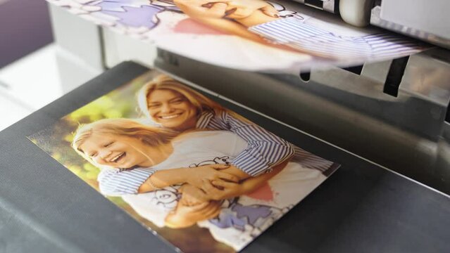The process of printing family photos on a printer in a darkroom.