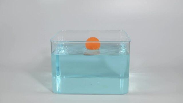 Slow motion footage of a ping pong ball being dropped into water
