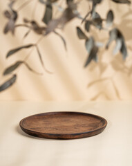 Abstract empty wooden plate with shadows and leaves on a beige background. Layout concept for promotional product presentation, sale or cosmetics display.