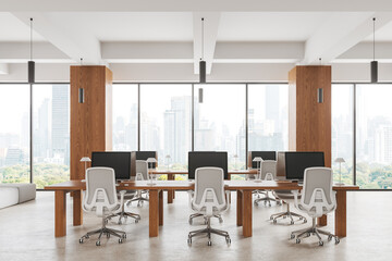 Cozy business interior with pc monitors and table in row near panoramic window