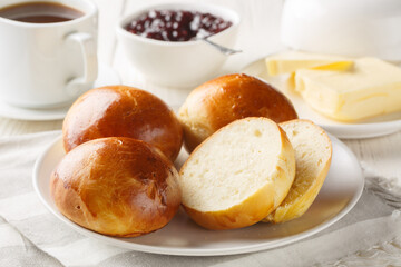 Soft and Delicious Norwegian Boller Cardamom buns served with butter, jam and coffee closeup on the wooden table. Horizontal