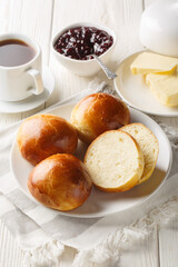 Cardamom Buns served with butter, jam and coffee closeup on the wooden table. Vertical