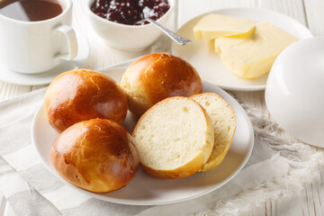 Hveteboller Norwegian Cardamom Sweet Buns served with butter, jam and coffee closeup on the wooden table. Horizontal