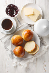 Norwegian cardamom rolls served with butter, jam and coffee closeup on the wooden table. Vertical top view from above
