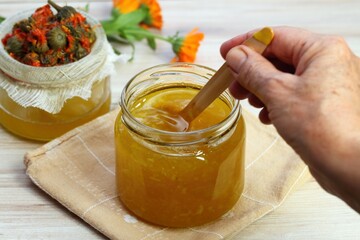 Mixing melted natural beeswax with warm herbal ointment. Woman hand holding a spoon. Natural...