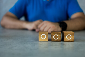 Man with three wood blocks with an empty circle for the list of three options. Checklist or to do...