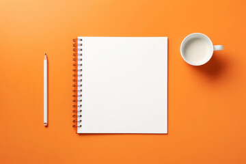 Blank notepad white pencil and cup of milk coffee latte on minimal orange background overhead view. Office stationary concept
