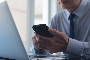 Businessman using mobile phone searching the information and working on laptop computer at office. Business man online working and using smartphone surfing the internet, business concept