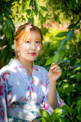 Portrait of a young woman wearing a Japanese yukata summer kimono in a hydrangea garden. Kyoto,...