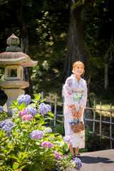 Portrait of a young woman wearing a Japanese yukata summer kimono in a hydrangea garden. Kyoto,...