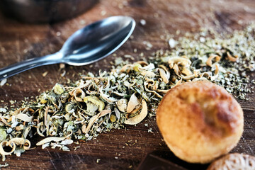 Feuilles de thé séchées sur planche en bois avec cuillère et petit gâteau 