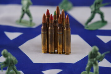 The concept of war. Soldiers as represented by a green plastic models and bullets on Israeli Flag...