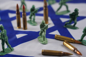 The concept of war. Soldiers as represented by a green plastic models and bullets on Israeli Flag...