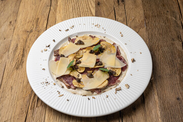 Veal carpaccio with Parmesan on a wooden table