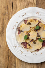 Veal carpaccio with Parmesan on a wooden table