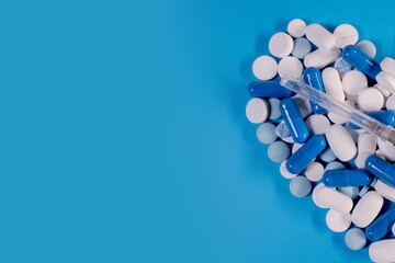 Pills in the shape of a heart and a syringe on a blue background. Pills for heart health. The concept of medicine and health care