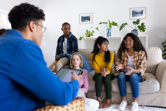 Thoughtful diverse group of teenage friends using tablet during therapy at home