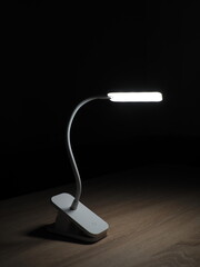 turned on rechargeable led table lamp on wooden table in dark room