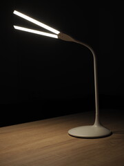 turned on rechargeable led table lamp on wooden table in dark room
