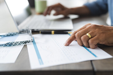 Senior biracial man at table working on laptop at home