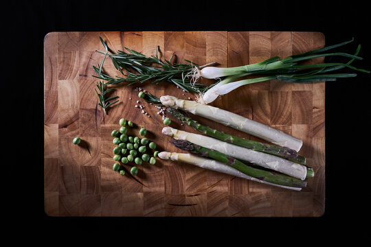 Asperges, poireaux et petits pois sur planche en bois