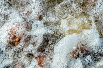 beautiful stones on the beach covered with foam