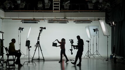 Professional filming pavilion with a white cyclorama. Shooting of a girl in a red dress who sings...