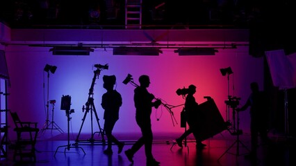 Professional filming pavilion with a neon cyclorama. The process of preparing for the shooting of a music video. Director, Cameraman and crew in Backstage. - obrazy, fototapety, plakaty