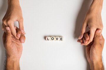 Closeup on two young lovers holding hands isolated on white background, 