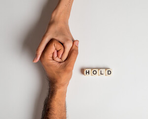 Closeup on two young lovers holding hands isolated on white background, 