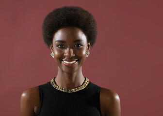 Close up portrait of smiling african american black woman with afro hairstyle and earrings chain jewelry isolated on beige background with copy space